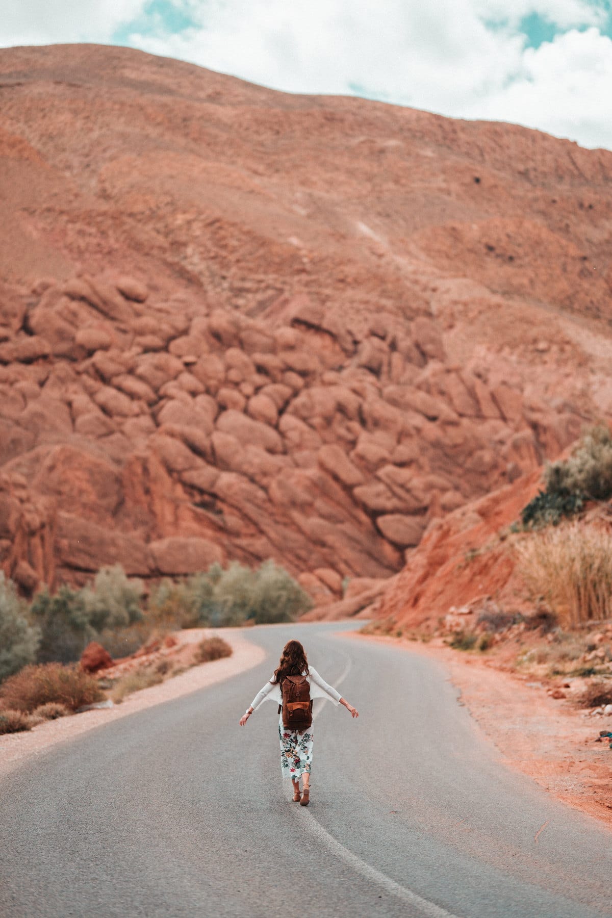 Viajera caminando por la carretera que atraviesa las gargantas rojizas del Dades