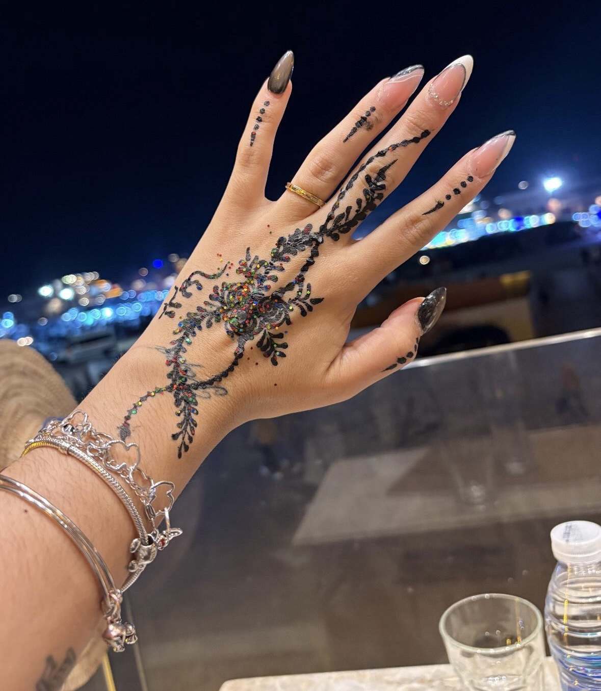 Mano decorada con un tatuaje de henna frente a las luces de la plaza Jemaa el-Fna